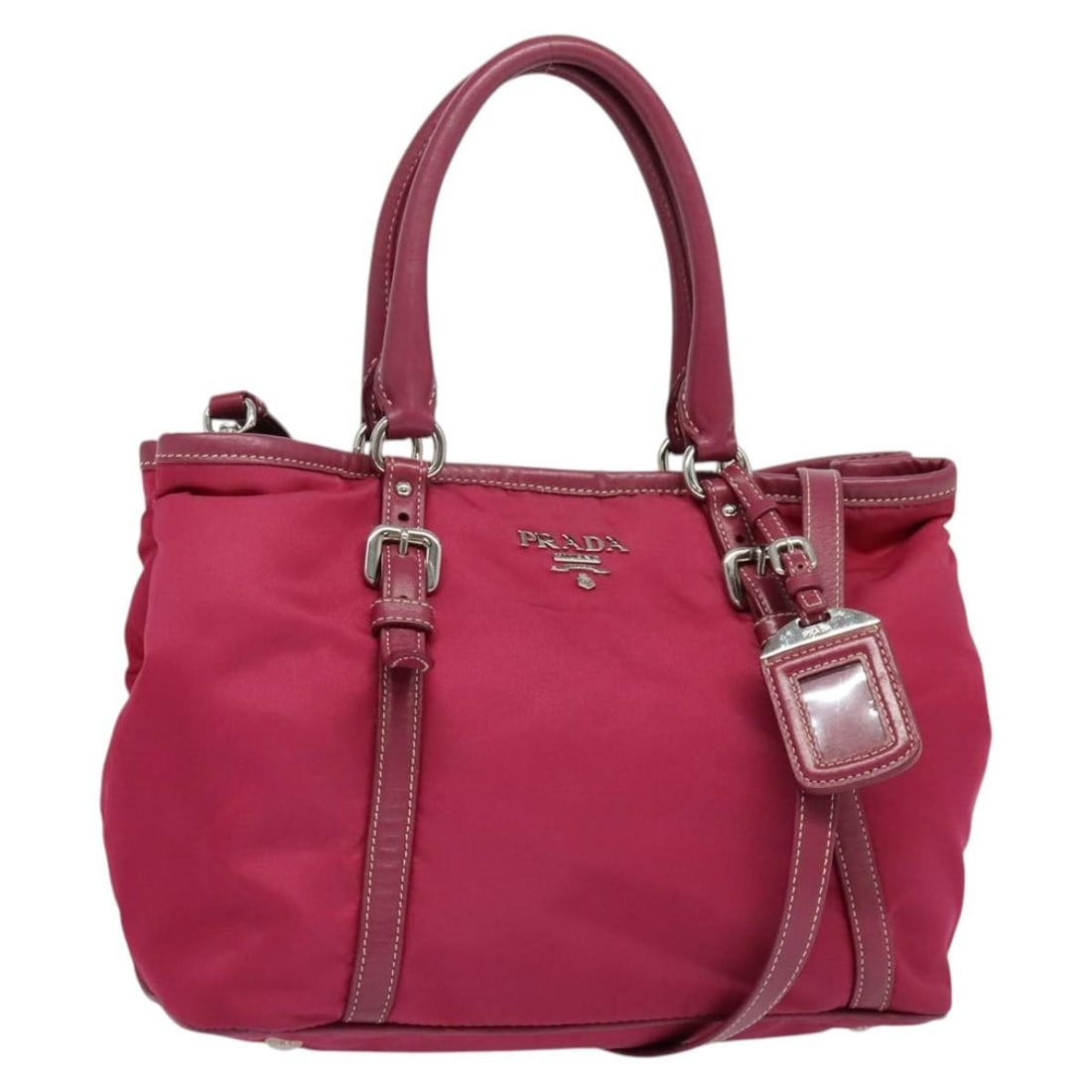 Prada pink silver nylon tote with shoulder strap and name tag: Prada pink silver nylon tote with shoulder strap and name tag This PRADA tote bag is crafted from durable nylon in a striking pink and silver color combination. Designed for versatility, it features b
