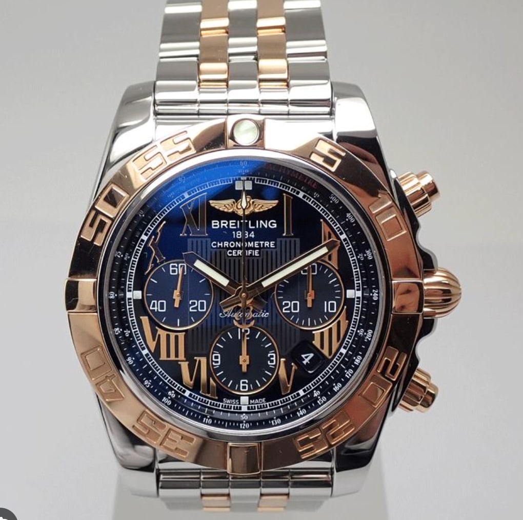 Breitling CB0110 Chronomat mens watch black Roman dial with 2016 card: Breitling CB0110 Chronomat mens watch black Roman dial with 2016 card Breitling Chronomat wristwatch featuring a black Roman dial and a rotating rose gold bezel. This men's watch is presented on a sta