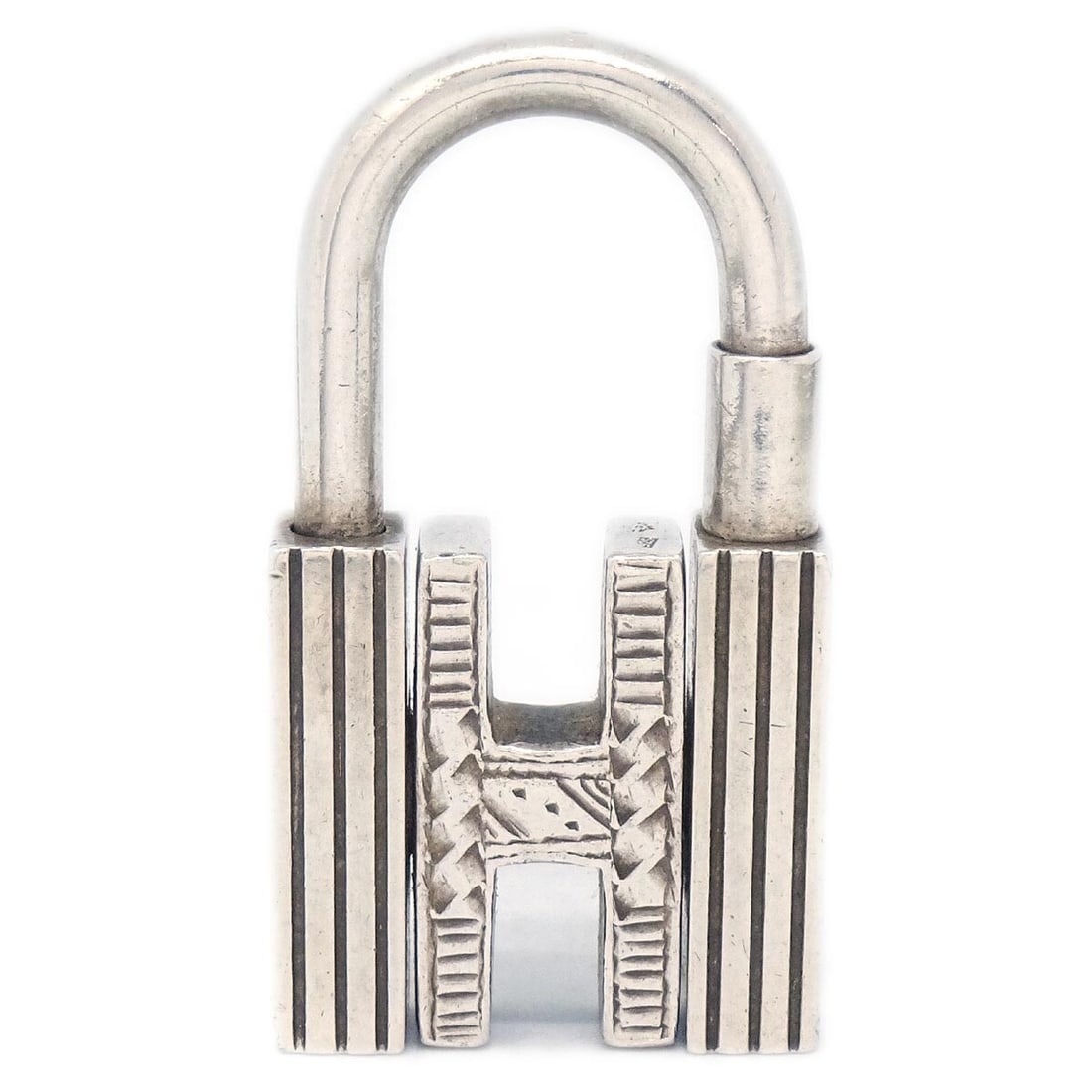 Hermes Touareg H Cadena Small Sterling Silver Padlock Charm: Hermes Touareg H Cadena Small Sterling Silver Padlock Charm Hermes Touareg H Cadena in sterling silver with the signature H motif and decorative detailing. This small padlock-style accessory is presen