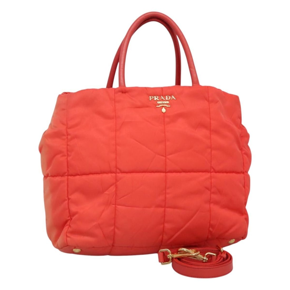 Prada Orange Nylon Handbag with Shoulder Strap and Guarantee Card: Prada Orange Nylon Handbag with Shoulder Strap and Guarantee Card This PRADA handbag is crafted from durable nylon in a striking orange and gold color combination. Designed for versatility, it can be 