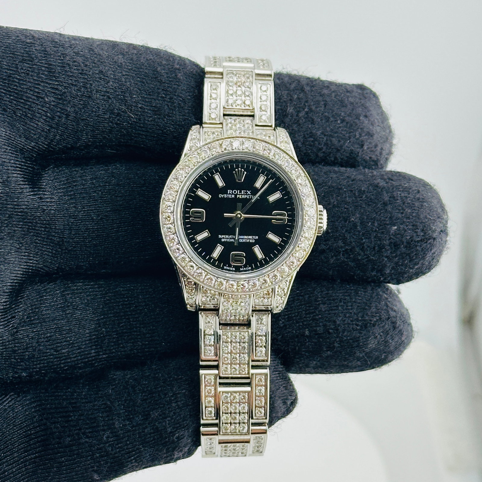 Rolex 176200 Oyster Perpetual Ladies Watch Black Arabic Dial aftermarket: Rolex 176200 Oyster Perpetual Ladies Watch Black Arabic Dial aftermarket Rolex Oyster Perpetual ladies wristwatch featuring a black dial with Arabic 3, 6, and 9 numerals, a diamond bezel, and an iced 