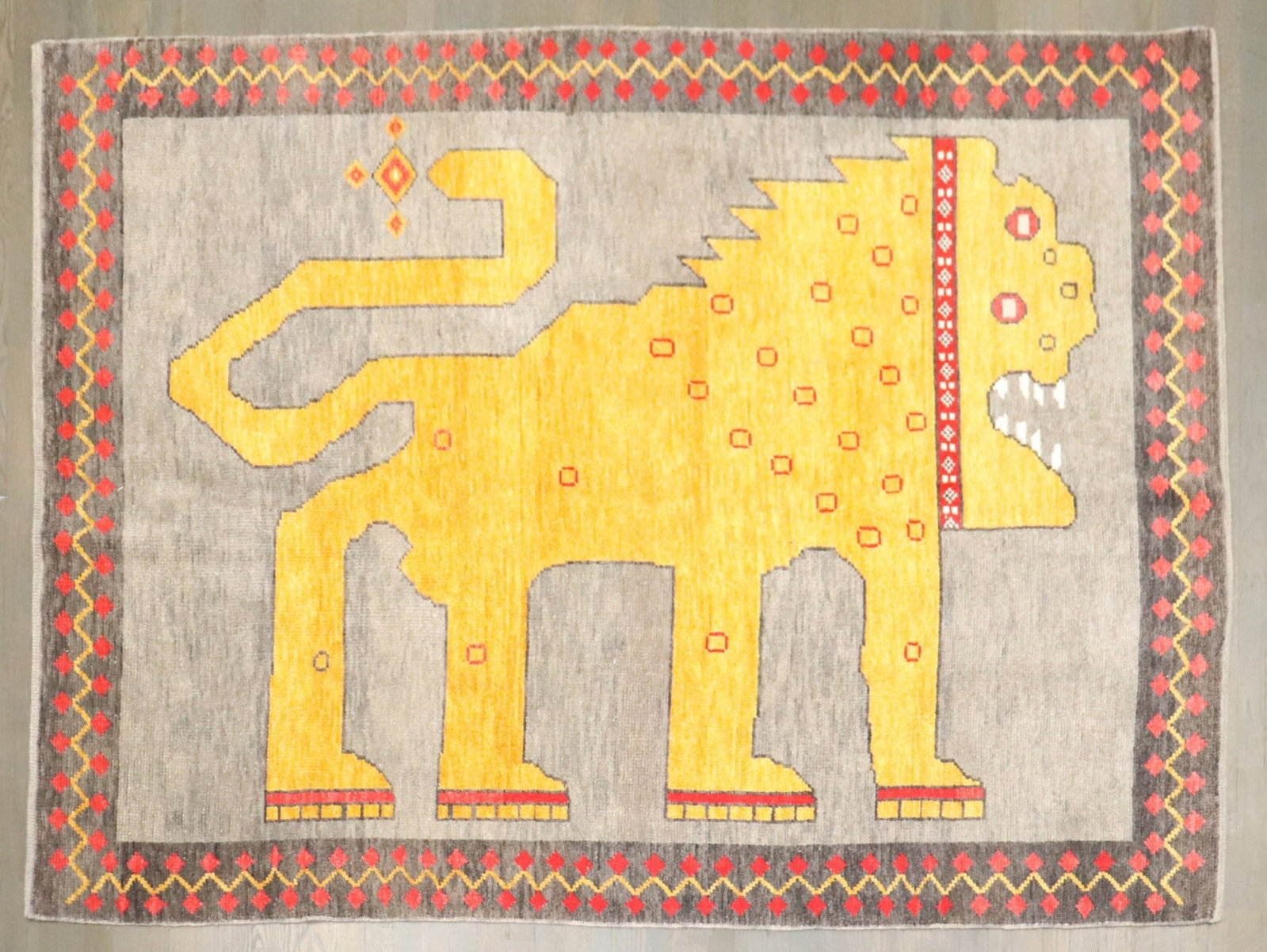 5' 7" x 8' Wool Turkish Pictorial Lion Rug Repro: 5' 7" x 8' Wool Turkish Pictorial Lion Rug Repro Hand-knotted Turkish pictorial rug with a boldly stylized lion motif in vivid, high-contrast color. The front-facing, symmetrical composition is render