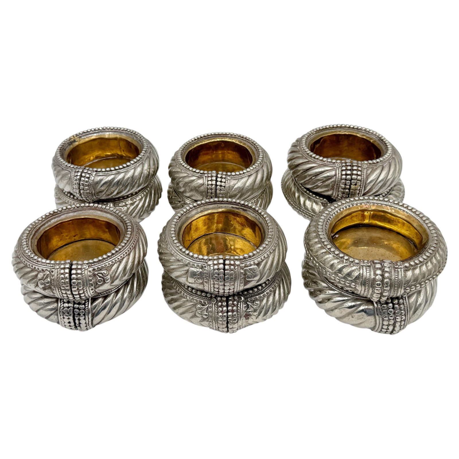 Set of 12 Indian silvered gilt brass dishes from tribal anklets: Set of 12 Indian silvered gilt brass dishes from tribal anklets Set of 12 Indian silvered and gilt anklets repurposed as coasters, ashtrays, or small dishes. Originally made as traditional tribal jewe