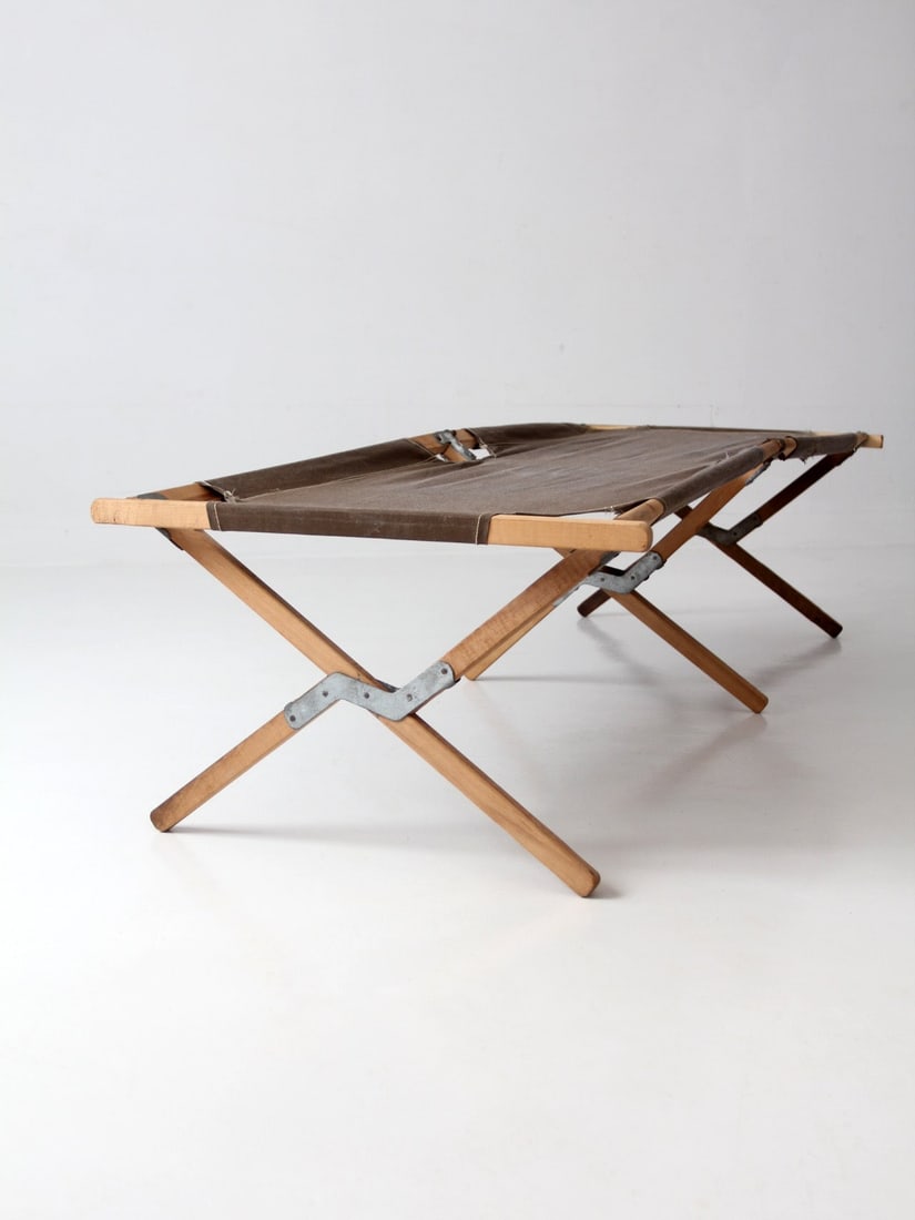 Byer folding camp cot campaign style wood frame: Byer folding camp cot campaign style wood frame Vintage Byer Manufacturing folding camp cot with a streamlined wood frame and classic campaign-style construction. It is a practical piece of