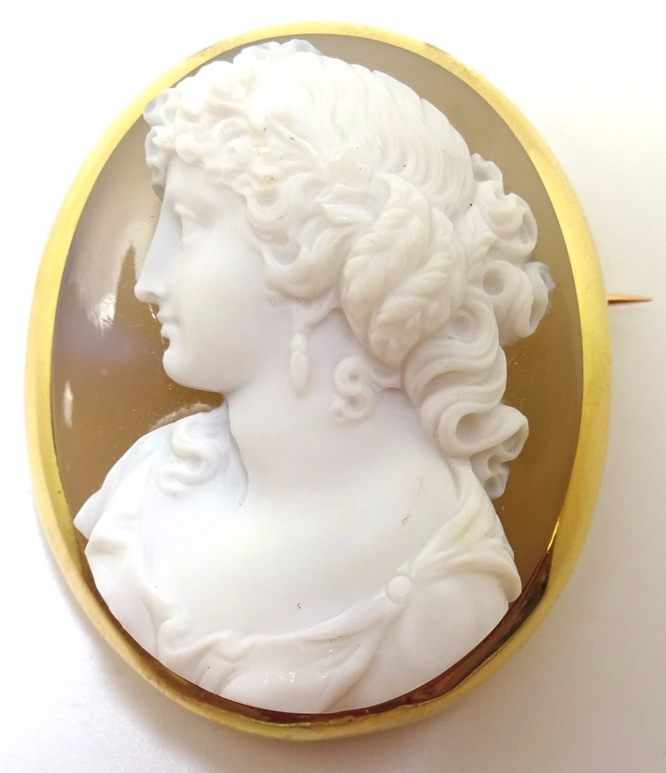 19th Century 18k Yellow Gold Oval Agate High Relief Cameo Brooch: 19th Century 18k Yellow Gold Oval Agate High Relief Cameo Brooch This rare 19th century cameo pin features a high relief, hand-carved banded agate in brown and white tones, set in solid 18k yellow gol