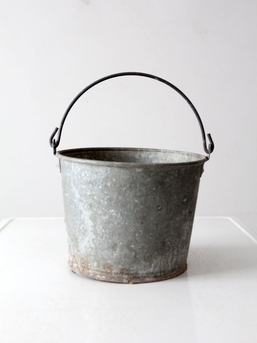 Vintage Galvanized Tin Bucket Rustic Farmhouse Decor: Vintage Galvanized Tin Bucket Rustic Farmhouse Decor This vintage galvanized metal bucket showcases a classic utilitarian design, complete with a curved handle for easy carrying. Originally utilized i