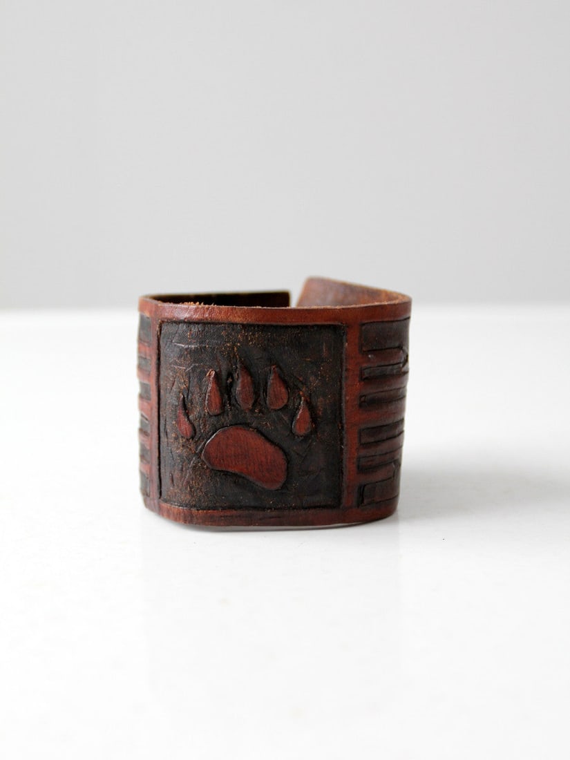1970s Vintage Tooled Leather Cuff Bracelet Bear Claw Design: 1970s Vintage Tooled Leather Cuff Bracelet Bear Claw Design This stunning vintage 1970s tooled leather cuff bracelet features a striking bear claw design prominently displayed on thick rust brown leat
