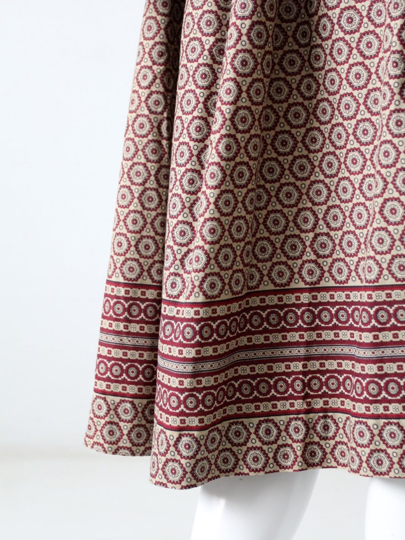 Maroon Geometric Pattern Belted Skirt from the 1960s: Maroon Geometric Pattern Belted Skirt from the 1960s This vintage 1960s maroon skirt features a bold geometric print and a full silhouette. It is designed with a belted waist and falls just below the 