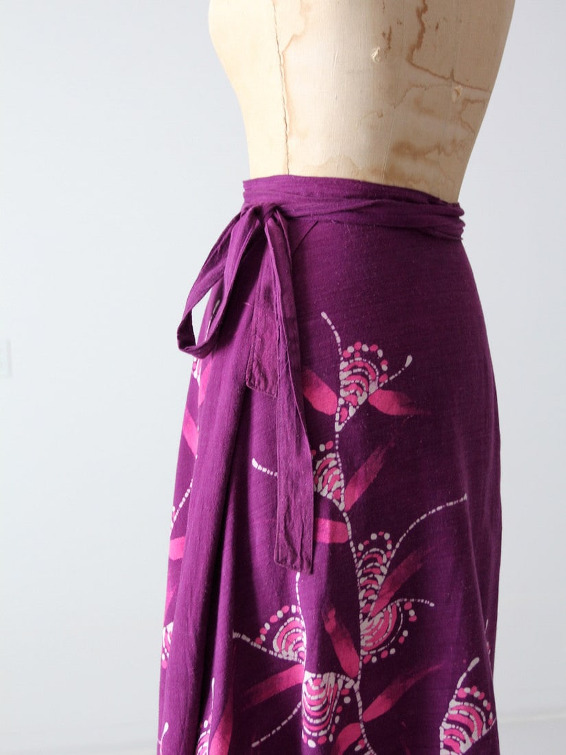 1970s Vintage Tropical Wrap Skirt Purple Cotton Floral Print: 1970s Vintage Tropical Wrap Skirt Purple Cotton Floral Print This vintage 1970s tropical wrap skirt is a stunning addition to any wardrobe. Crafted from silky purple cotton, it showcases a vibrant pin