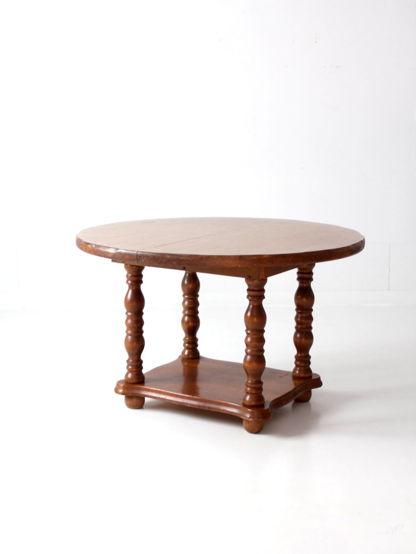1970s Vintage Lodge Style Round Dining Table with Baluster Legs: 1970s Vintage Lodge Style Round Dining Table with Baluster Legs This exquisite Vintage Lodge Style Dining Table, dating back to the 1970s, embodies the charm of Colonial tavern style. It features a ro
