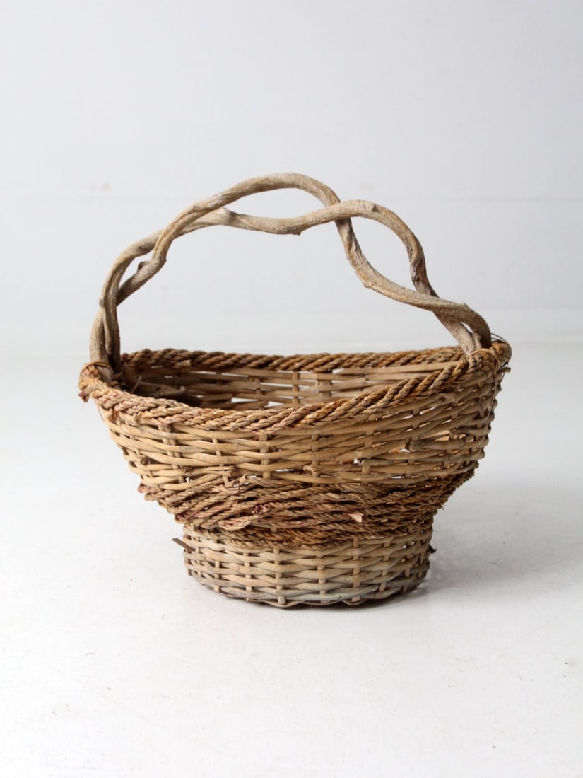 Charming Vintage Rustic Woven Basket with Twisted Wooden Handle: Charming Vintage Rustic Woven Basket with Twisted Wooden Handle This vintage rustic woven basket is an ideal decorative catchall for your home. Featuring intricate braided detailing around the top and