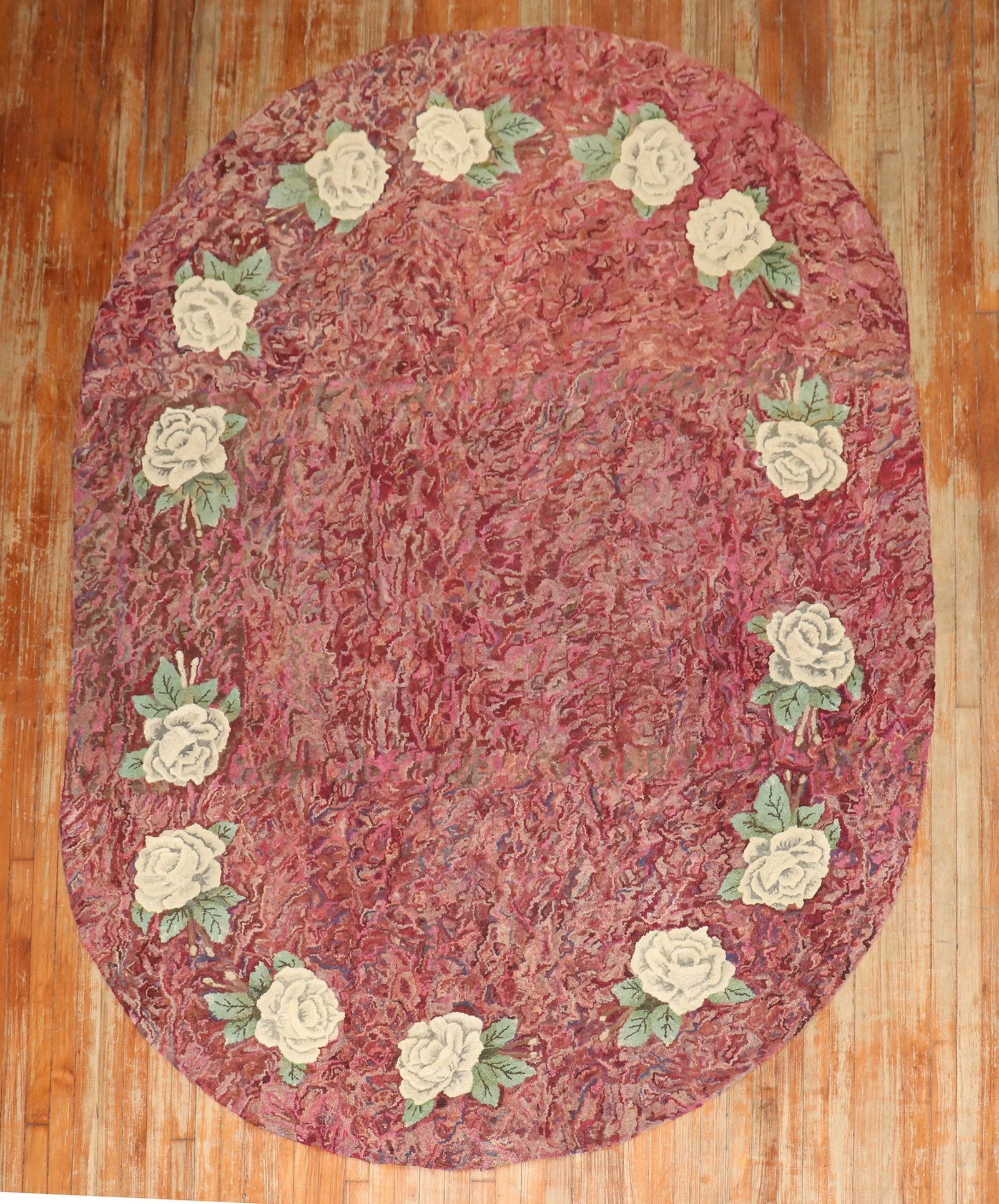 6' 8" x 9' 7" Oval American Hooked Rug Initialed L.H.C.: 6' 8" x 9' 7" Oval American Hooked Rug Initialed L.H.C. Mid-20th century American hooked rug in a distinctive oval form, featuring the initials L.H.C. The design includes feminine floral motifs framed