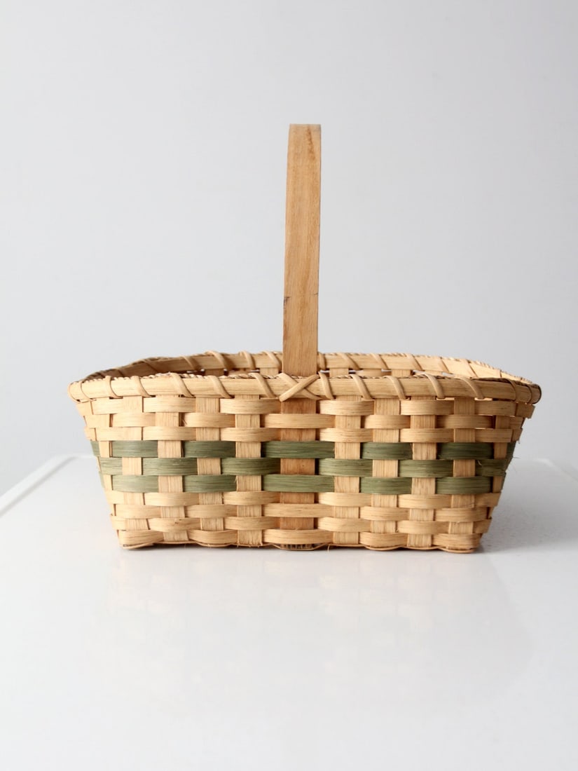 Handmade Vintage Basket With Green Accent and Tall Handle 16.75in Wide: Handmade Vintage Basket With Green Accent and Tall Handle 16.75in Wide This vintage handmade gathering basket features a warm honey-toned weave accented by a subtle green band, giving it a distinctive