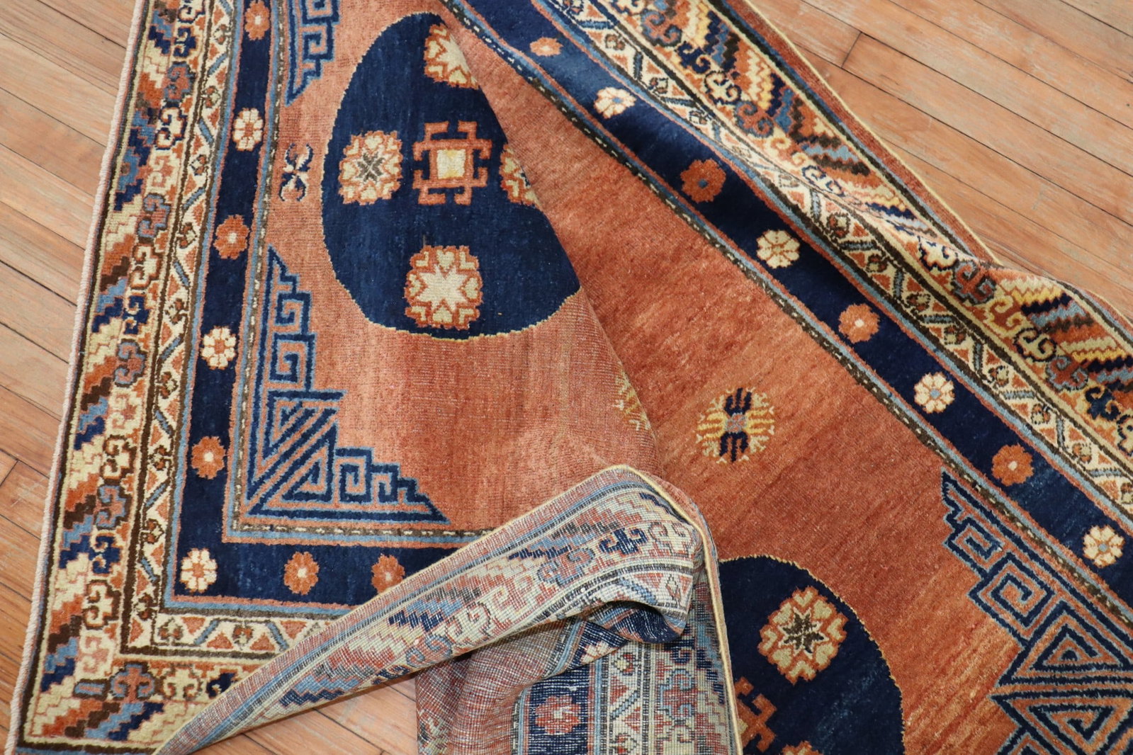 4' 4" x 6' 2" Early 20th Century Khotan Rug Part of Pair: 4' 4" x 6' 2" Early 20th Century Khotan Rug Part of Pair Early 20th century Khotan rug in salmon and navy blue hues, offered as part of a pair. This pre-owned accent rug features the classic decorativ