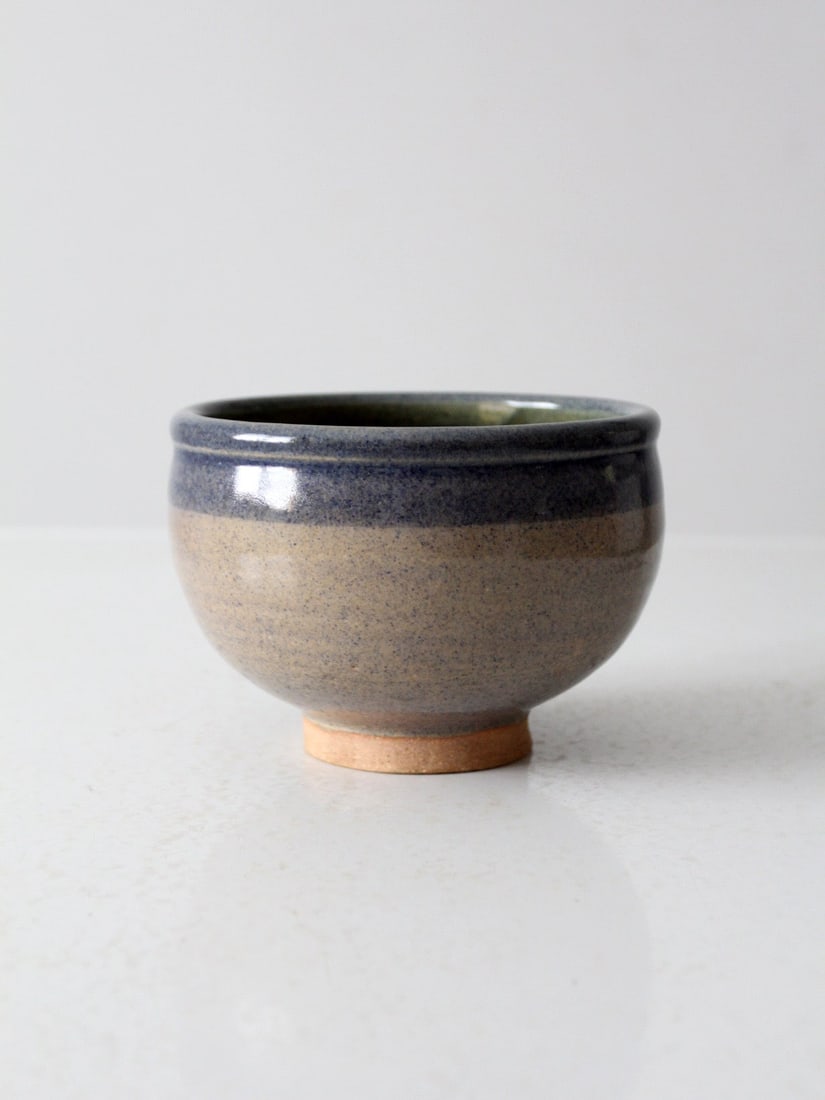 Signed Vintage Studio Pottery Footed Bowl Speckled Taupe Blue Rim: Signed Vintage Studio Pottery Footed Bowl Speckled Taupe Blue Rim This vintage studio pottery bowl showcases a beautiful speckled taupe glaze complemented by a striking blue stripe along the rim. It i