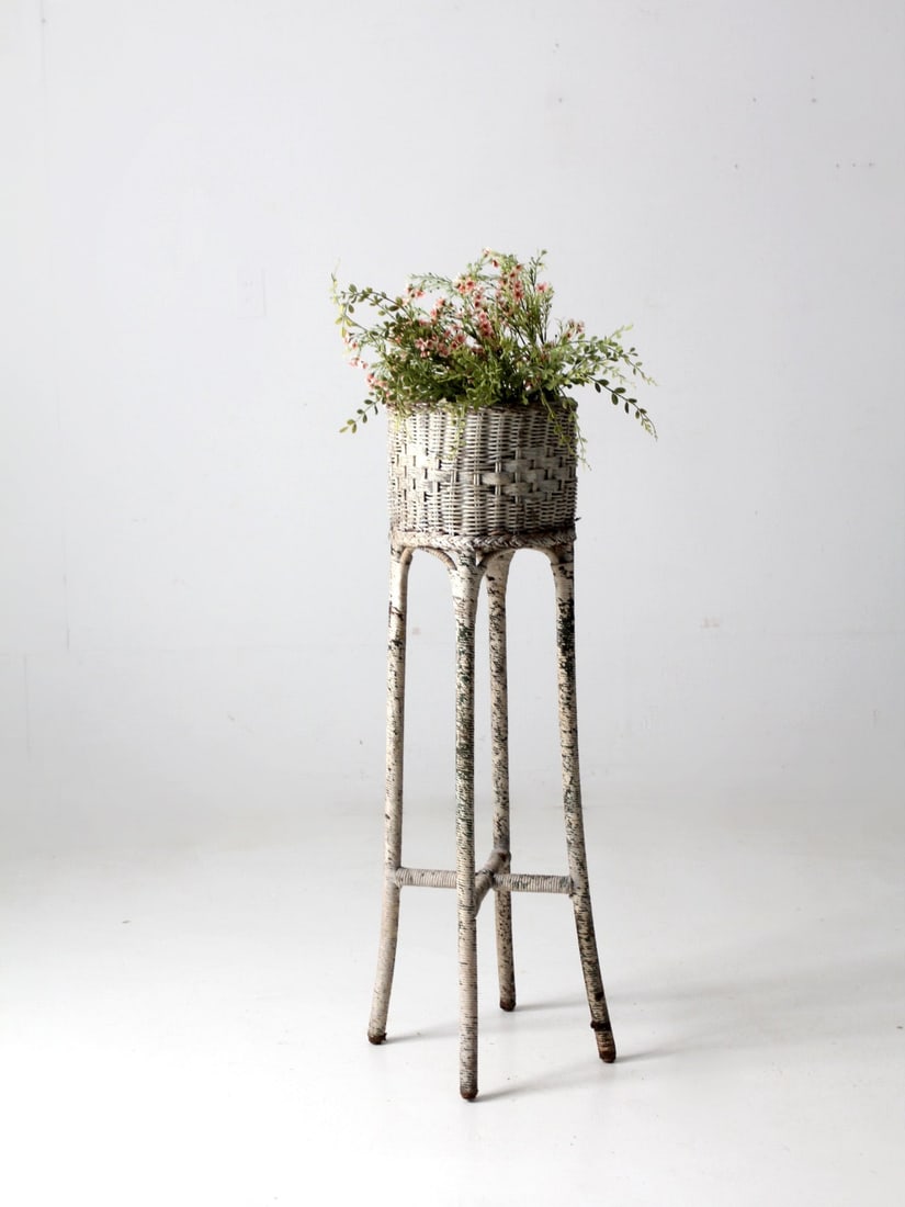 Victorian Era White Wicker Plant Stand with Tall Architectural Design: Victorian Era White Wicker Plant Stand with Tall Architectural Design This antique Victorian tall white wicker planter dates to the early 20th century. It features a finely woven basket elevated on sl