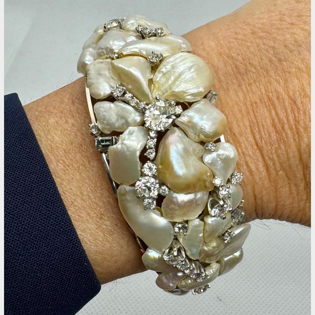 1960's 14K White Gold Baroque Pearl Diamond Bangle 4.50 Ct: 1960's 14K White Gold Baroque Pearl Diamond Bangle 4.50 Ct This exquisite 1960's bangle is crafted in 14K white gold and features a stunning baroque pearl centerpiece accented by a total of 42 diamond