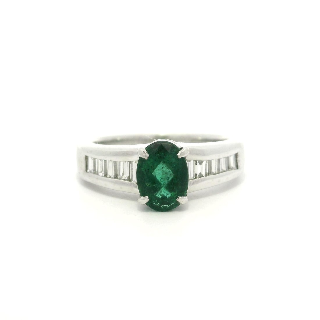Platinum Emerald Solitaire Ring with Baguette Diamonds 1.64ctw: Platinum Emerald Solitaire Ring with Baguette Diamonds 1.64ctw This exquisite platinum band ring features a stunning natural oval emerald at its center, measuring approximately 7.55 x 5.5 mm and weigh