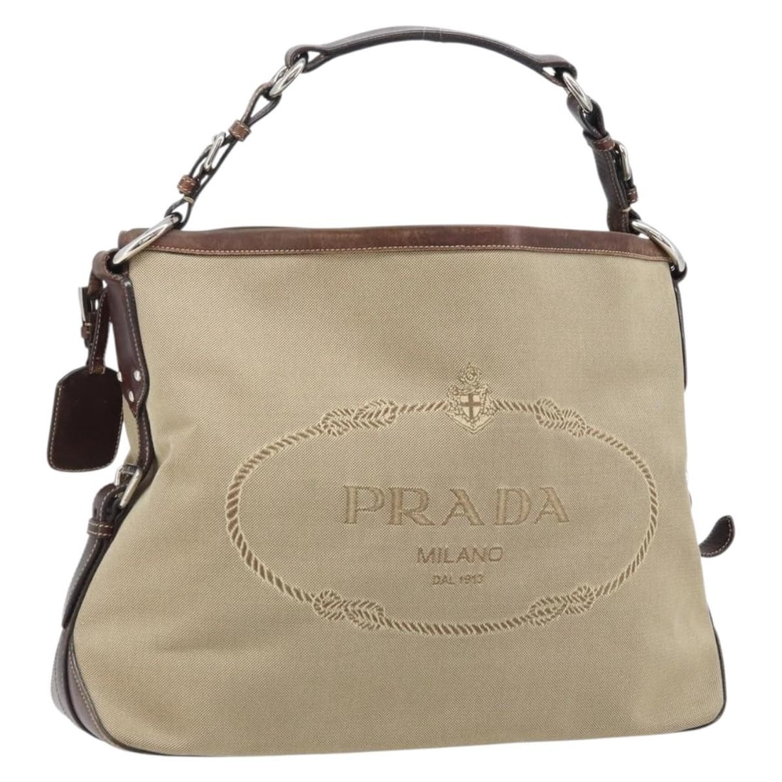 PRADA Beige Canvas Shoulder Bag with Silver Tone Name Tag: PRADA Beige Canvas Shoulder Bag with Silver Tone Name Tag Authentic Prada shoulder bag in beige and silver canvas with a name tag accessory. Made in Italy, this women's bag has a heavily used conditio