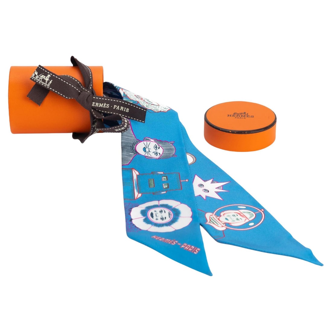 Hermes Comic Twilly Scarf Blue 33.9 in New France: Hermes Comic Twilly Scarf Blue 33.9 in New France Introducing the exquisite Hermes Comic Twilly in a vibrant blue hue, showcasing a playful comic pattern featuring various characters elegantly lined u