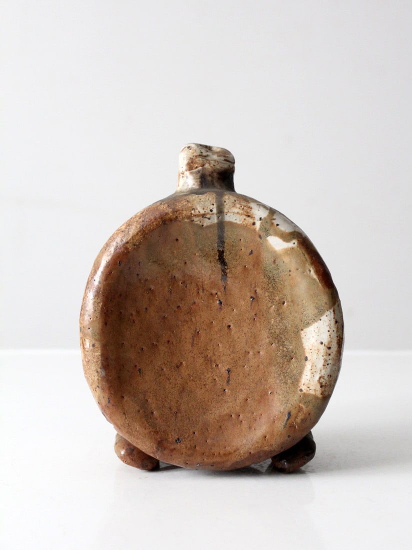 Mid Century Studio Pottery Flattened Bottle Vase Earth Tone Glaze: Mid Century Studio Pottery Flattened Bottle Vase Earth Tone Glaze This mid-century studio pottery vase features a flattened bottle shape with a sculptural profile. The vase is finished in layered eart