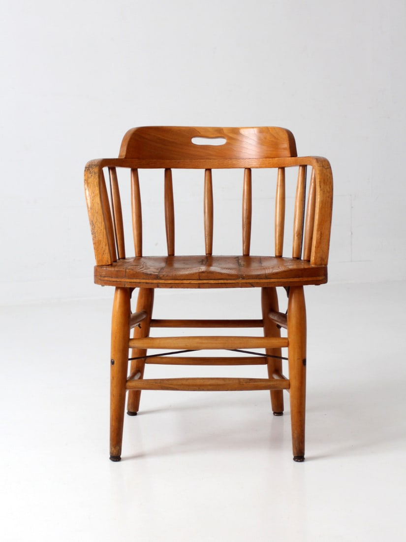 Early American Oak Captain Chair with Turned Spindle Back: Early American Oak Captain Chair with Turned Spindle Back Vintage Early American captain's chair in oak with a continuous curved arm, sculpted crest rail with an integrated handhold, turned spindle ba