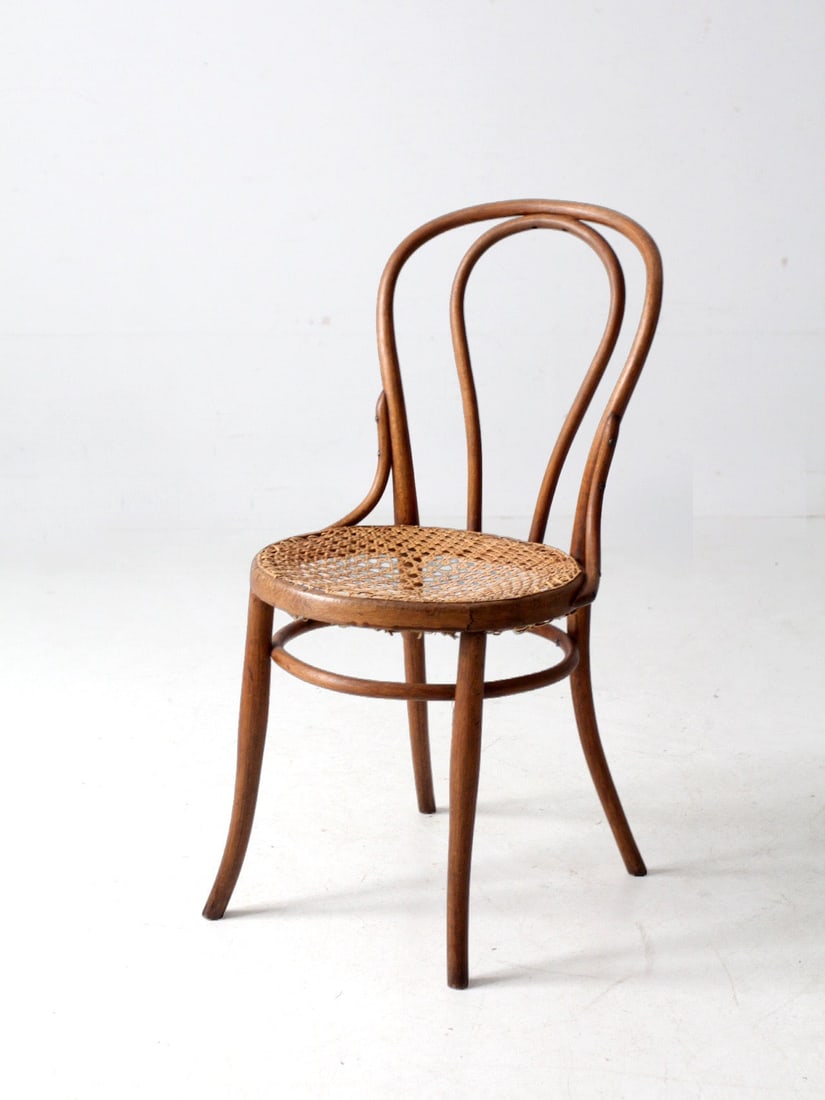 Antique Bentwood Cafe Chair with Hand-Caned Seat: Antique Bentwood Cafe Chair with Hand-Caned Seat This antique bentwood cafe chair features an elegantly arched bentwood back and softly curved legs, embodying a classic European profile. The warm wood