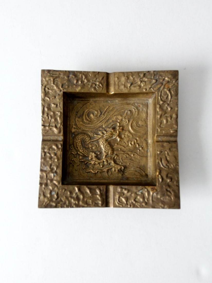 Square Brass Ashtray with Raised Chinese Dragon Relief: Square Brass Ashtray with Raised Chinese Dragon Relief Vintage Chinese brass ashtray with a weighty square form and richly worked dragon imagery in raised relief. A sculptural dragon appears among cur