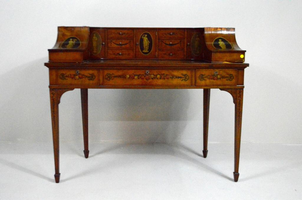Sheraton Revival Carlton House Desk: The rectangular top with a shaped gallery comprised of two storage bins, two doors and six drawers flanking a central door, each painted with classical figures and garlands, over a frieze of one wide 