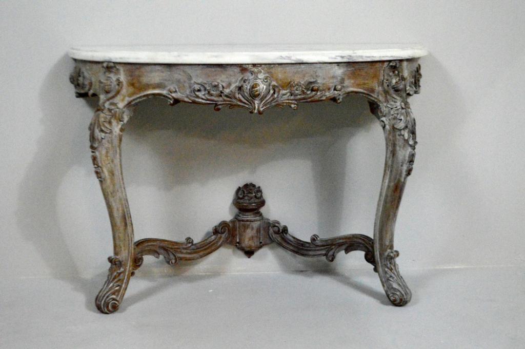 Continental Rococo Revival Marble Top Pier Table: With a moulded white marble demilune top over a shaped apron decorated with carved acanthus and flowers centered on a stylized armorial shield, the whole raised on two cabriole legs with foliage about
