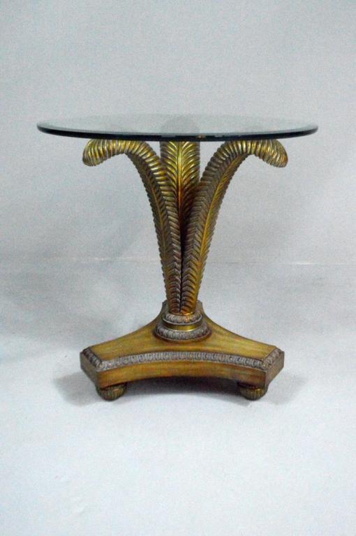 Glass Top Palm Frond Center Table: With a moulded circular glass top supported by three gilt painted palm fronds, the whole raised on a moulded and carved tripartite base whit three carved ball feet.