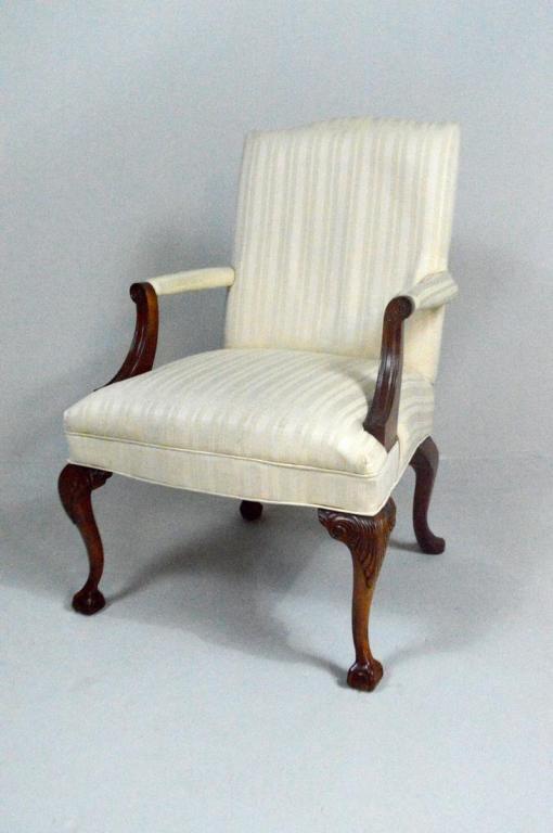George III Style Library Armchair: With a fully upholstered back and seat flanked by upholstered arms supported by shaped and scrolling stumps, the whole raised on two carved cabriole legs ending in ball and claw feet to the front and 