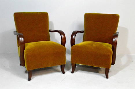 Pair of Mid-Century Modern Club Chairs: Each with brown velvet upholstered back and seat flanked by pair of shaped walnut stained arms, the whole raised on four splay legs