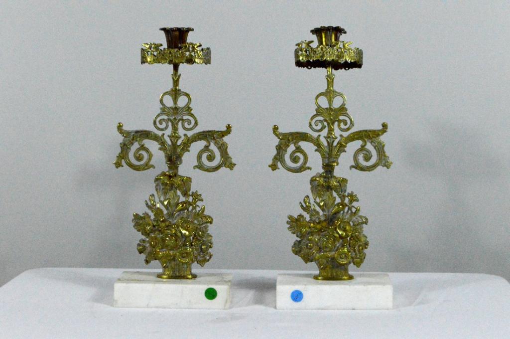 Brass Single Light Garniture: Each with a bloom form sconce surrounded by a foliate fender, the stem of bound foliage emanating from a urn of flowers, raised on rectangular white marble base.