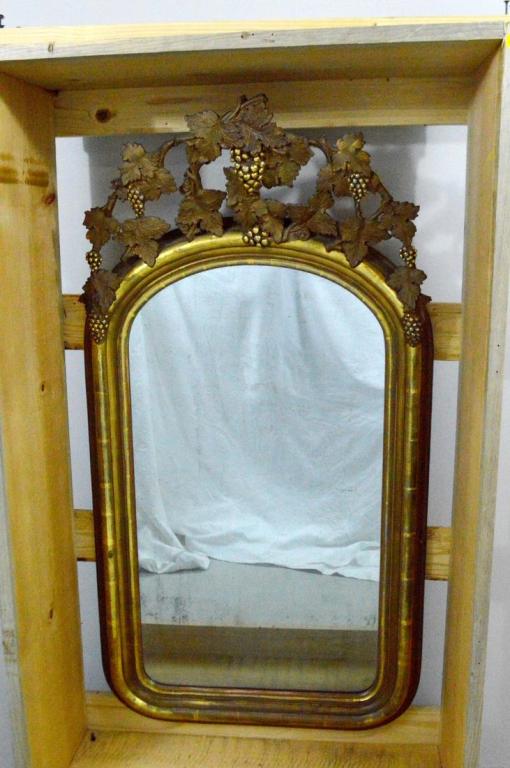 Gilt Wood Mirror with Grape Motif: With a pediment of grape leaves and bunches of grapes over a rounded glass flanked by a moulded frame. Clay appears to be red. NOTE: Not entirely removed from packing crate, no apparent damage.