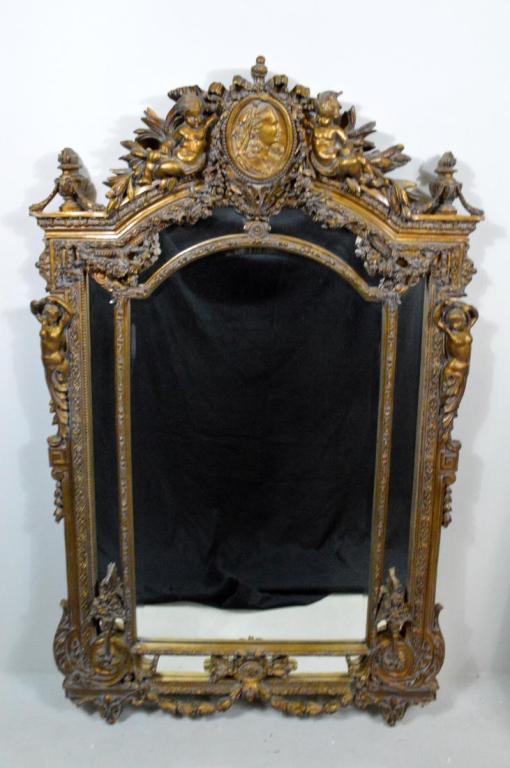 Renaissance Revival Pier Mirror: With a pediment centered on a cameo of a woman flanked by two putti with multitudes of foliage and two urns, the central glass flanked by four narrow glazed panels and siderails of topless maidens, th