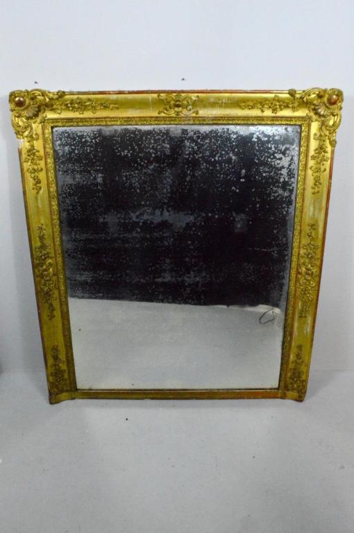 19th Century Gilt Wood Mantle Mirror: Of rectangular shape with original glass, the frame with flowing foliage and and escutcheons to the upper corners, resting on a plain moulded base.