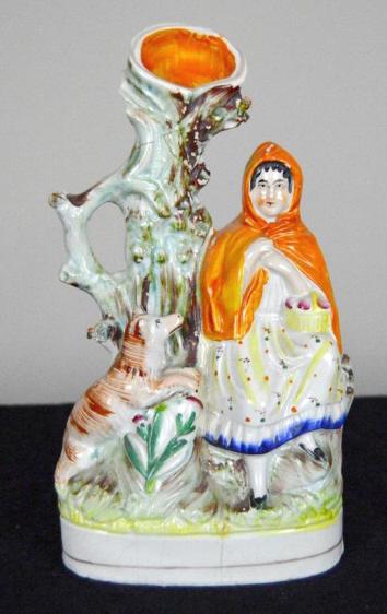 Staffordshire Spill Vase of Little Red Riding Hood: Of Little Red Riding Hood seated beside a tree. Good condition with evidence of major repairs to tree and back verso. 9.75 x 5.5 x 2 in.