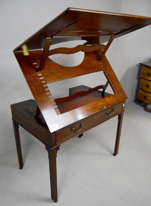 George III Style Architect: In Mahogany, with a shaped and moulded double accordion top over a single shaped drawer, the whole raised on four square legs ending in casters. 32 x 40 x 27 in. Condition: Repair to back leg at friez