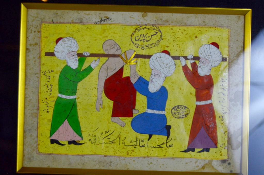 Medical Subject Page From Islamic Manuscript: Page from Islamic manuscript showing an orthopedic medical procedure on the left arm on the man being carried. Appeawrs to be handwritten and colored. Frame:13 x 15 in. Image in frame 7 x 9 in.