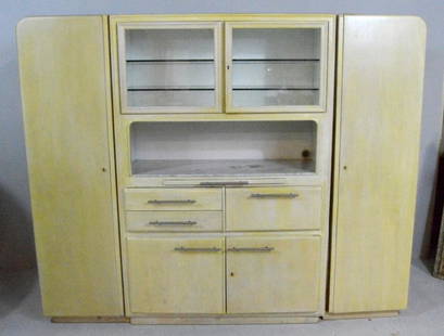 Blonde German Mid-Century Kitchen Cabinets: In three parts, the central part with two glass doors opening to reveal a lighted compartment with two glass shelves over an open compartment with a marble base over a slide out work shelf over two