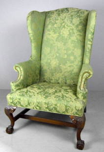 American Wingback Armchair, 19th Century: The whole covered in green damask, with a shaped crest rail and pronounced wings and scrolling, upholstered arms flanking an upholstered seat, the whole raised on two cabriole legs with eagle face