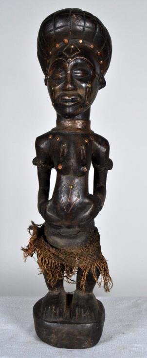 Chokwe Statue of a Woman: African, Zaire, wood, 20th Century; Of a standing woman with a fiber skirt embellished with copper. Zaire. 22 x 5 x 5 in. Condition: Wear consistent with age and use Property of Anthony French. Sr.