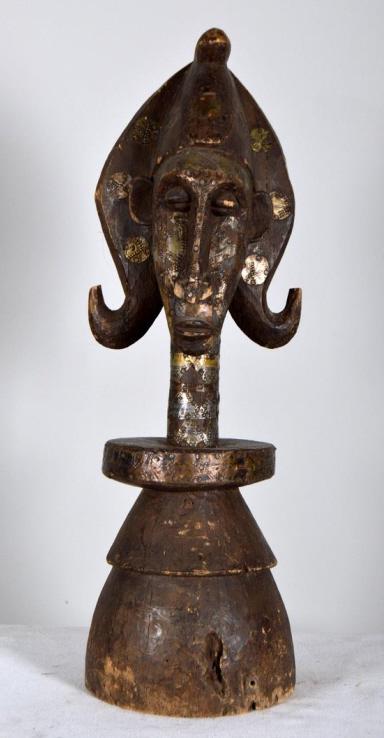 Fang Female Reliquary Head: Central African, Cameroon, wood, 20th Century; Of a female head in a headdress, the whole decorated with embossed metal plates. 26.5 x 8.5 x 8.5 in. Condition: Wear consistent with age and use Propert