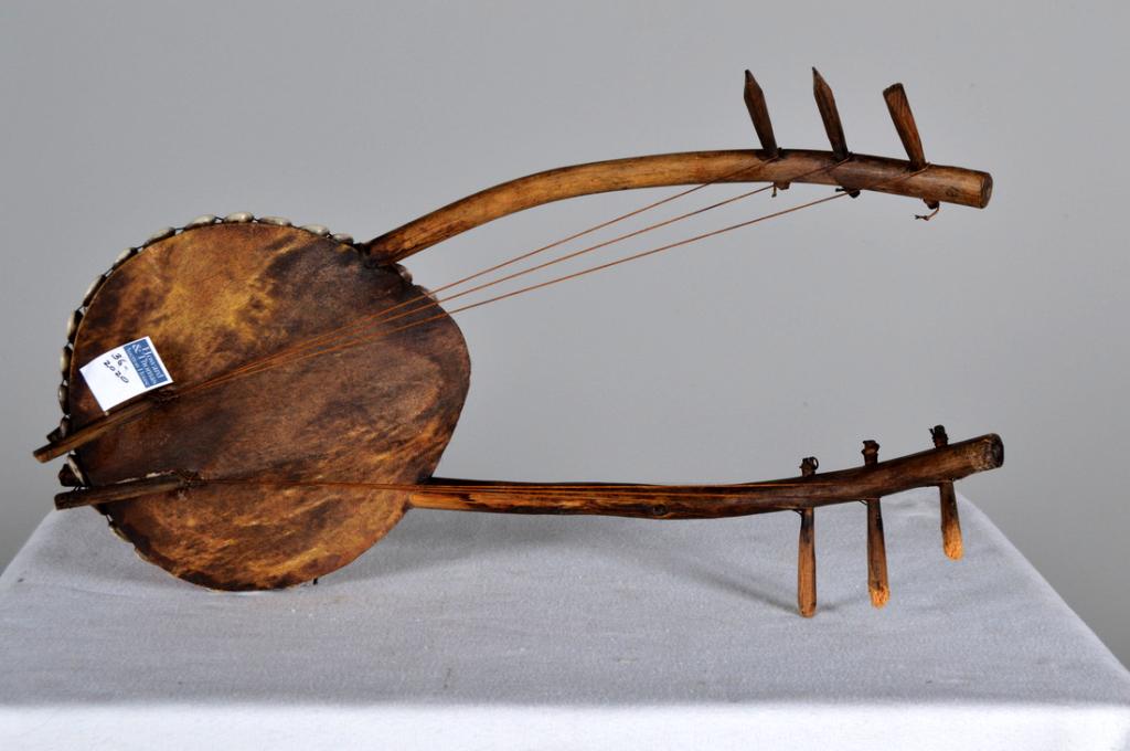 Vintage Double Necked Zambezi Kora: With gourd and leather body embellished with cowrie shells, double necked, 6 strings. 18 x 8 x 3 in. Condition: Wear consistent with age and use Property of Anthony French. Sr.