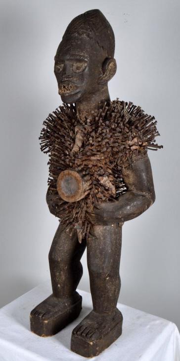 Songye Statue of Nkisi Yombe: Congo, West Africa, 20th Century; Of a standing male, the body with bilongo cavity surrounded by nails (each representing a resolved "litigation" personal or community wide) 40 x 17 x 11 in. Condition