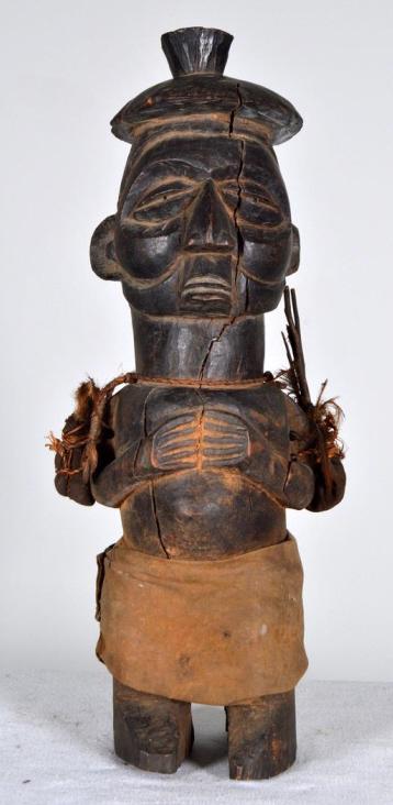 Songye Nkisi Power Figure: African, Zaire, wood, 20th Century; Of a male with hands at the chest, an amulet and feathers at the arms. 21 x 5.5 x 5.5 in. Condition: Wear consistent with age and use Property of Anthony French. Sr