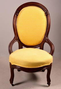 19th Century American Side Chair: Rococo Revival, with shaped and carved oval back with yellow fabric, over a round seat, the whole raised on four carved legs. 41 x 21 x 22 in. NOTE: One castor repaired, otherwise wear