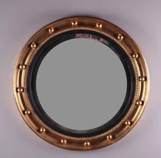 Regency Style Round Beveled Mirror: Gold frame with balls surrounding a flat beveled morror. Dimensions: 23.5 x 23.5 x 2.25 in. NOTE: Good overall. One chip to frame