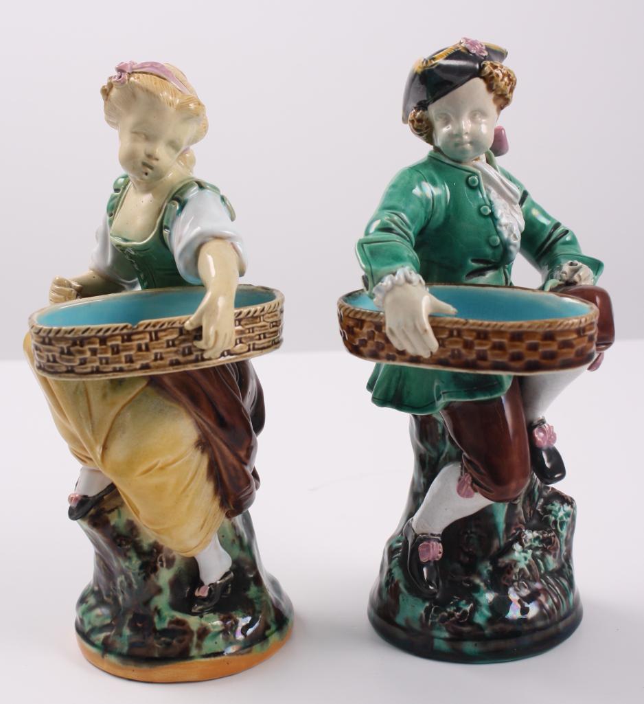 Pair of Minton Majolica Figurines: Consisting of a man and a woman, both holding baskets Dimensions: 7.5 x 4 x 4 in. NOTE: No apparent flaws